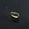 Gold ring with a dark stone on a dark textured surface