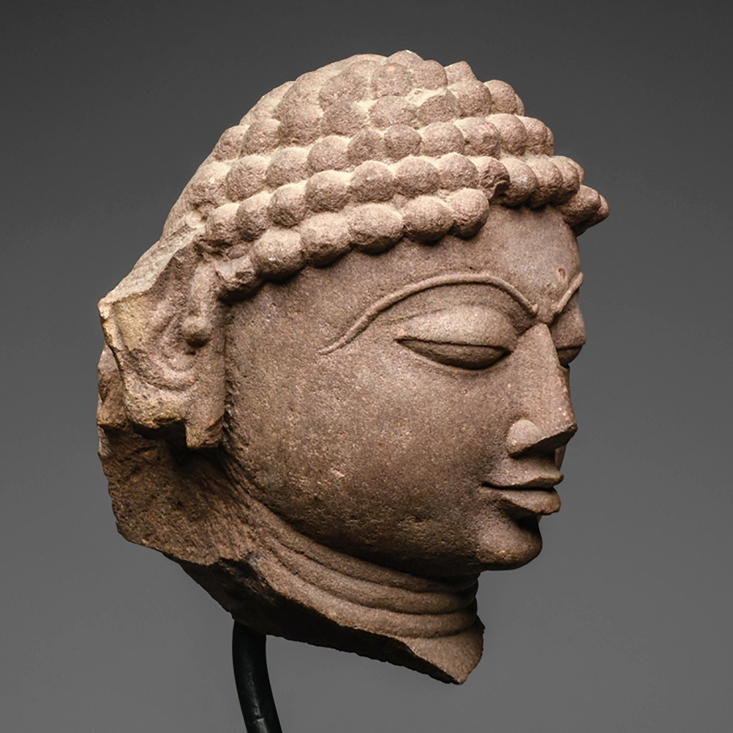 A mottled red sandstone head of a Jina, India, 11th/12th century CE - Sands of Time Ancient Art